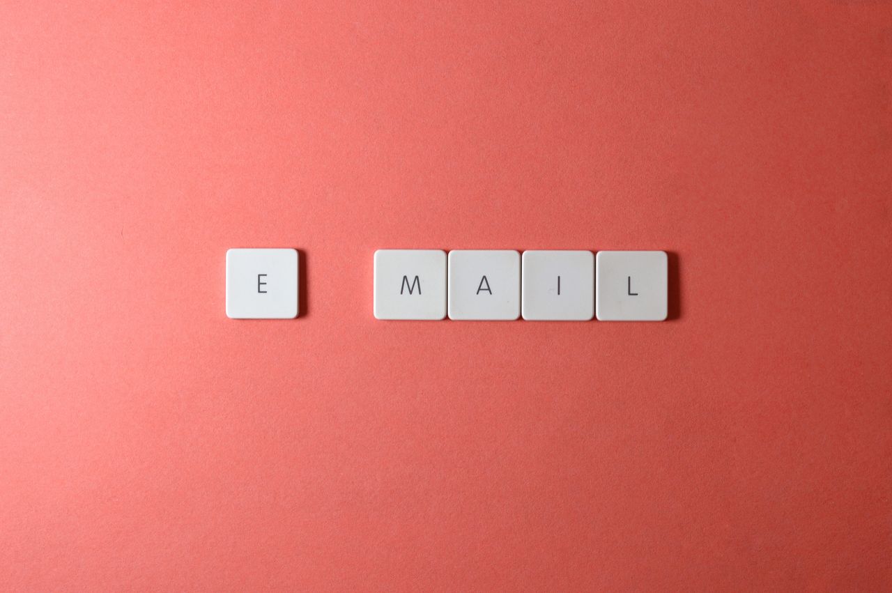 Photo en flat lay de touches de clavier formant le mot « email » sur un fond corail.